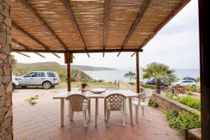 een patio met een tafel en stoelen en uitzicht op de oceaan bij La vista di Mondo in Torre Dei Corsari