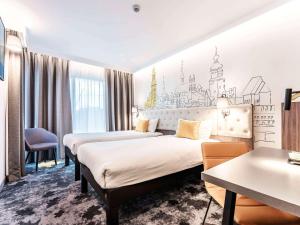 ルブリンにあるibis Styles Lublin Stare Miastoのベッド2台とデスクが備わるホテルルームです。