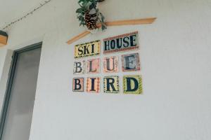 Ski House Bluebird في غودواري: علامة على منزل الطيور الزرقاء معلقة على الحائط