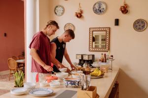 due persone in piedi in una cucina a preparare il cibo di Hotel & Hostal Boutique Casa Garza a Mérida