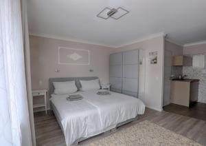 a white bedroom with a white bed and a table at H-Apartments Bismarckstrasse in Trier