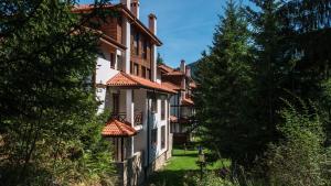 een gebouw met rode daken en bomen bij “Family аpart - Смолянски езера“ in Smolyan