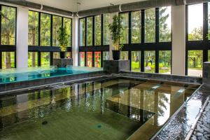 einen Pool in einem Gebäude mit Glasfenstern in der Unterkunft Oxigén Family Hotel Noszvaj in Noszvaj