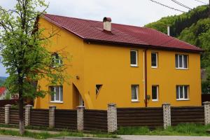 una casa gialla con una recinzione in legno di Сільська Садиба a Kvasy