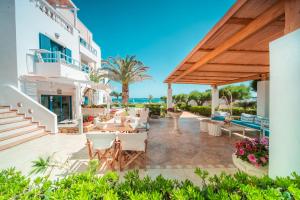 un patio di un hotel con tavoli e sedie di Pyrgos Beach Hotel Apartments a Mália