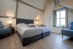 ein Schlafzimmer mit einem großen Bett und zwei blauen Stühlen in der Unterkunft B&B Zee van Tijd Domburg in Domburg