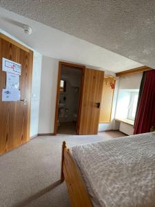 1 dormitorio con 1 cama y puerta al baño en Hotel Bernina Hospiz, en Berninahäuser