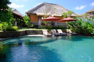 una piscina con sillas y sombrillas frente a una casa en Puri Andong Villa, en Ubud