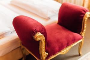 une chaise rouge assise à côté d'un lit dans l'établissement Das Kleine Hotel in ruhiger Stadtlage, à Wiesbaden