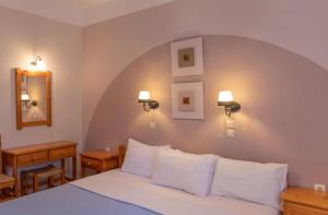 una camera da letto con un grande letto con cuscini bianchi di Limnonari Beach Rooms a Skopelos Town