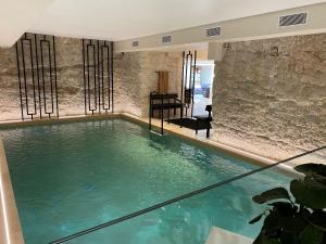 - une grande piscine d'eau dans une chambre dotée d'un mur en pierre dans l'établissement Hotel Spa Genovese, à Bonifacio