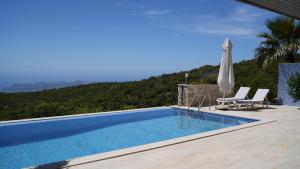 einen Pool mit 2 Stühlen und einem Sonnenschirm in der Unterkunft Villa Emilie Kas in Kaş