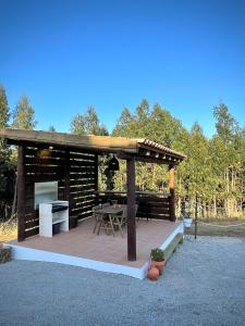 um gazebo de madeira com uma mesa e um grelhador em Monte da Rocha em Santiago do Cacém