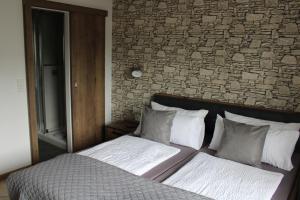 a bed in a bedroom with a brick wall at Bachmeier's Gasthaus Traube Niederfell in Niederfell