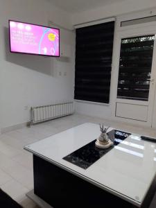 una cucina con bancone bianco e TV a parete di Apartman ZAFIROVI a Gevgelija