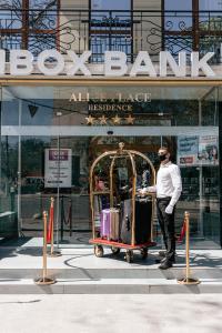 Ein Mann schiebt einen Wagen mit Gepäck vor einem Gebäude in der Unterkunft Alice Place Hotel in Odessa