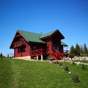 una cabina rossa con tetto verde su un campo verde di Lake House Villa pas Eugenija a Migiškiai