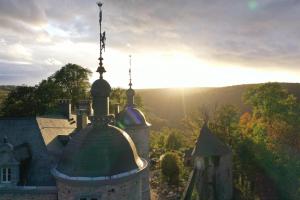 um edifício com um telhado verde com o pôr-do-sol ao fundo em Le Château de Mirwart em Mirwart