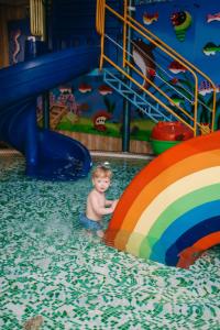 Ein kleiner Junge im Wasser auf einer Wasserrutsche in der Unterkunft Alice Place Hotel in Odessa