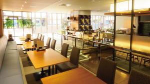 een restaurant met houten tafels, stoelen en ramen bij Koriyama View Hotel Annex in Koriyama