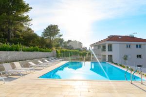 - une piscine avec des chaises longues à côté d'un bâtiment dans l'établissement Malo More Resort, à Trogir