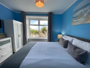 una camera blu con un grande letto con finestra di The Lyncroft a Newquay