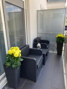 - une terrasse couverte avec des chaises en osier et des fleurs sur le balcon dans l'établissement Swiss Luxury Apartment, à Mosonmagyaróvár