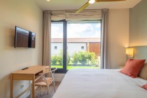 a bedroom with a bed and a desk and a window at OCEANSUITESLANGRE in Galizano