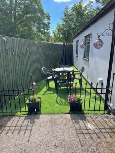 einen Garten mit einem Tisch, Stühlen und einem Zaun in der Unterkunft Ty Mynydd Lodge Holiday Home in Cardiff