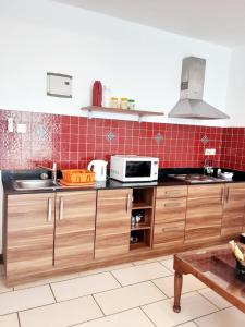 a kitchen with wooden cabinets and a microwave at Cowrie Shell Beach Apartments Official in Bamburi