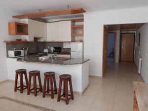 een keuken met 3 barkrukken en een aanrecht bij Sunset Village Apartment - Brisa Da Ericeira in Ericeira