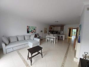 een woonkamer met een witte bank en een tafel bij Sunset Village Apartment - Brisa Da Ericeira in Ericeira