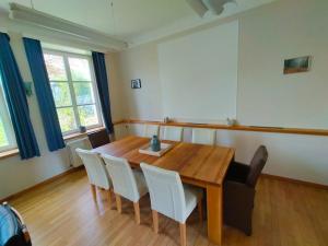 uma sala de jantar com uma mesa de madeira e cadeiras brancas em Gite rural a Bivels em Bivels