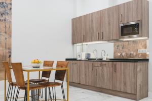 een keuken met houten kasten en een tafel met stoelen bij Apartamentos Abreu Suites in Sevilla