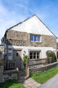 uma casa de pedra com uma cerca de madeira em frente em Thornes Cottage em Huddersfield