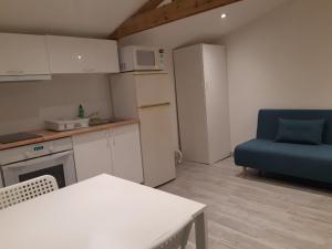 uma cozinha com uma mesa e uma cadeira azul em Logement proche Lyon-aéroport-Centrale Bugey em Dagneux