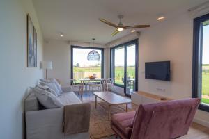 a living room with a couch and chairs and a tv at OCEANSUITESLANGRE in Galizano