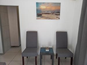 2 chaises et une table avec une horloge. dans l'établissement Tropical Paradise Guest House, à Nelspruit