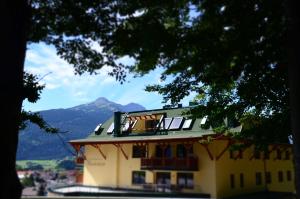 um grande edifício amarelo com uma montanha ao fundo em Villa Buchenhain em Ehrwald