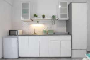 een witte keuken met witte kasten en een wastafel bij Jázmin Apartman in Makó