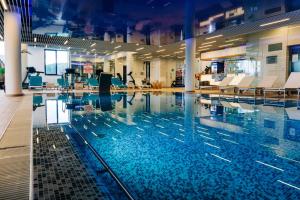 a swimming pool with chairs and tables in a building at Elexus Apartments Poiana Brasov in Poiana Brasov