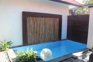 a swimming pool in front of a house with a fence at Jukung Villas Kuta in Kuta