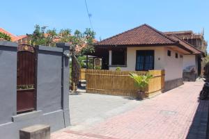 a house with a wooden gate and a brick sidewalk at Jukung Villas Kuta in Kuta