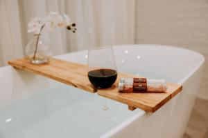 ein Glas Wein auf einem Holztablett neben einer Badewanne in der Unterkunft The Homestead in Berry