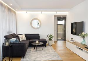 a living room with a black couch and a tv at Sea&City Deluxe Apartment - Top Center Varna in Varna City