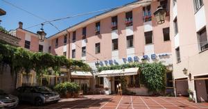 un gran edificio con coches estacionados frente a él en Hotel Tre Re, en Como