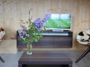 um vaso de flores roxas em uma mesa em frente a uma TV em Holiday Home Maiensäss Superior by Interhome em Urmein