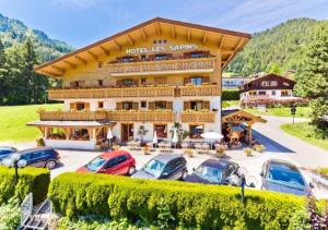 a large building with cars parked in a parking lot at Hotel les Sapins in La Clusaz