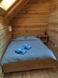 a bed in a log cabin with blue pillows on it at Lāču namiņš/Bear house in Liepāja