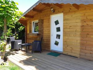 um chalé de madeira com uma porta branca e cadeiras em Logement proche Lyon-aéroport-Centrale Bugey em Dagneux